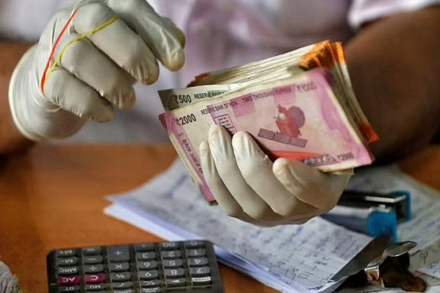 A trader wearing protective hand gloves counts Indian currency notes at a market during a 21-day nationwide lockdown to limit the spreading of coronavirus disease (COVID-19), in Kochi, India, Mar 27, 2020. REUTERS