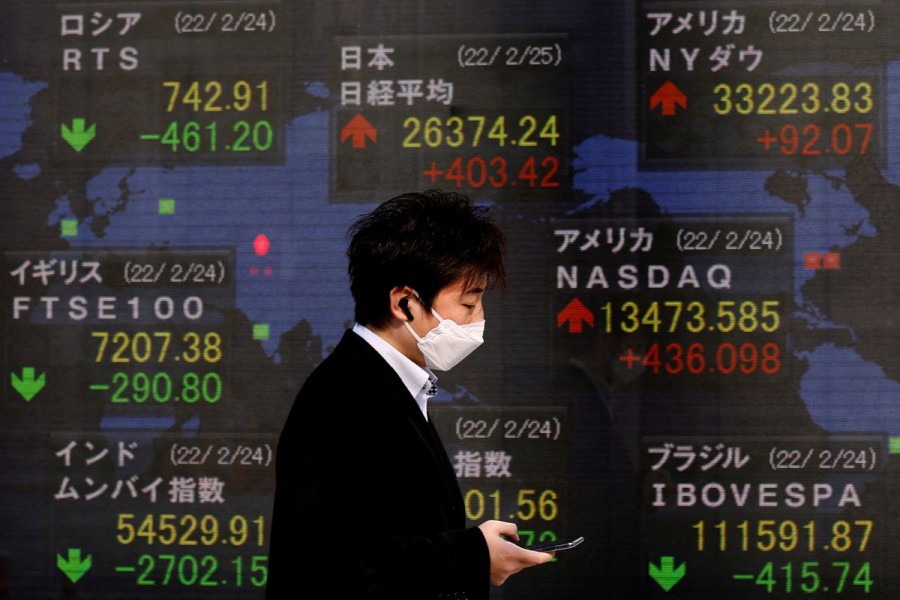 A man wearing a protective mask, amid the coronavirus disease (COVID-19) outbreak, walks past an electronic board displaying stock market data outside a brokerage in Tokyo, Japan, February 25, 2022. REUTERS/Kim Kyung-Hoon/
