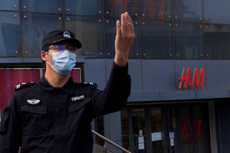 A police officer calls to colleagues for backup outside a store of the clothing giant H&M in a shopping area in Beijing, China, April 9, 2021. REUTERS/Thomas Peter