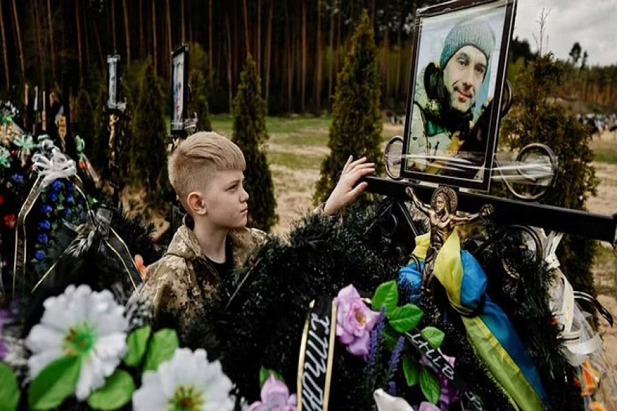 Savelii, 10, mourns his father Ihor Krotkikh, 47, who according to his mother Alla Krotkikh, 42, was killed by shelling, as he stands by his grave during the death memorial weekend which marks a week after the Orthodox Easter, amid the Russian invasion of Ukraine, at the cemetery in Irpin, outside Kyiv, Ukraine May 1, 2022.REUTERS