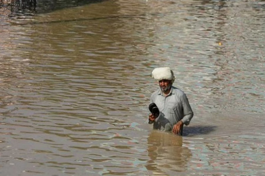 A man wades along a flooded road, following rains and floods during the monsoon season in Nowshera, Pakistan August 29, 2022. REUTERS/Fayaz Aziz