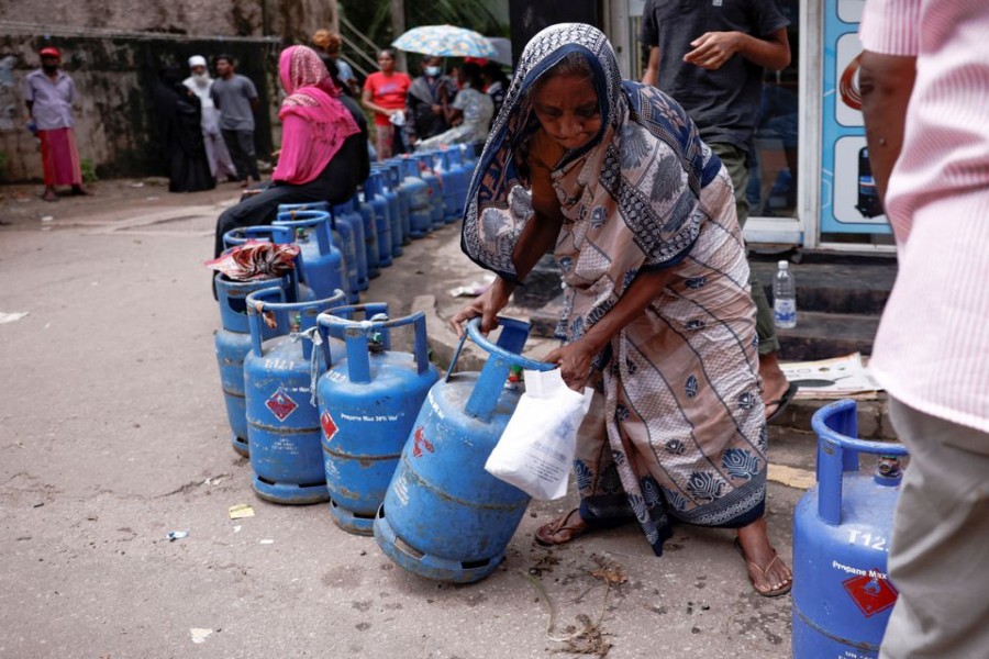 A woman moves a gas tank as she stands in line to buy another tank near a distributor, amid the country's economic crisis, in Colombo, Sri Lanka, June 1, 2022. REUTERS/Dinuka Liyanawatte