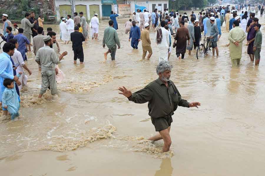 A man balancing himself as he, along with others, walking on a flooded road, following rains and floods during the monsoon season in Charsadda, in Pakistan recently -Reuters file photo