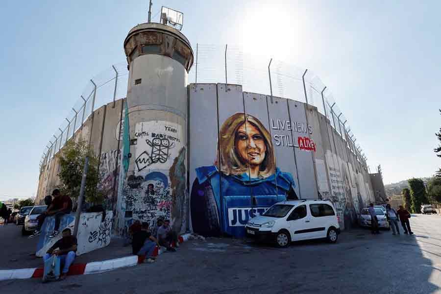 Palestinians sitting in front of a mural depicting the slain Palestinian-American journalist Shireen Abu Akleh on July 13 this year ahead of the visit of US President Joe Biden at Bethlehem in the Israeli-occupied West Bank –Reuters file photo