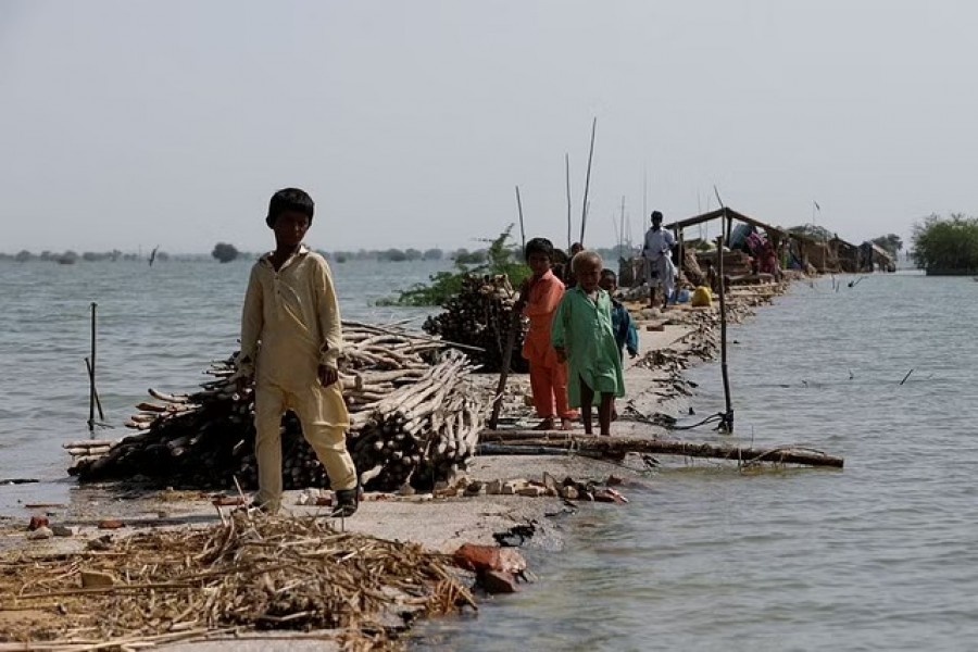 Children stand as their family takes refuge along a damaged road amid flood, following rains and floods during the monsoon season in Bajara village, at the banks of Manchar lake, in Sehwan, Pakistan Sept 6, 2022. REUTERS