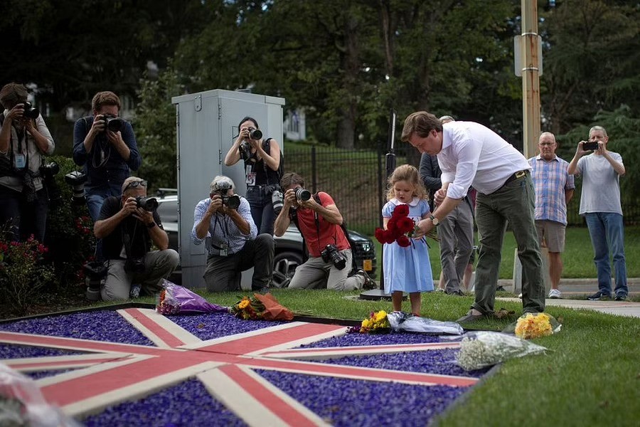 Edward Rodgers helps his daughter, India, lay flowers following the announcement of the death of Queen Elizabeth, at the British Embassy in Washington, US, September 8, 2022. REUTERS