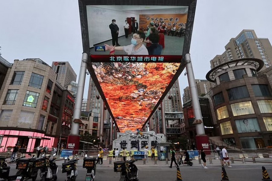 A giant screen shows news footage of Chinese President Xi Jinping visiting Xinjiang Uyghur Autonomous Region, at a shopping centre, in Beijing, China, July 15, 2022. REUTERS