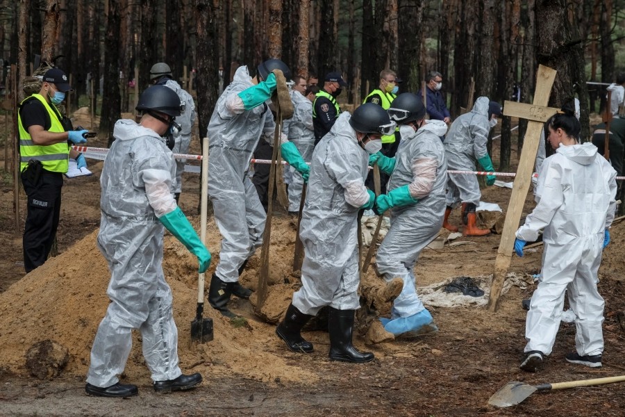 Members of Ukrainian Emergency Service work at a place of mass burial during an exhumation, as Russia’s attack on Ukraine continues, in the town of Izium, recently liberated by Ukrainian Armed Forces, in Kharkiv region, Ukraine September 17, 2022. (REUTERS)