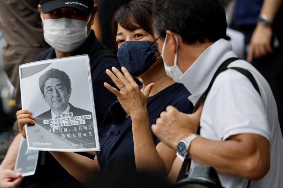 A woman holds a farewell message for late former Japanese Prime Minister Shinzo Abe, who was shot while campaigning for a parliamentary election, outside the Zojoji temple where the funeral of Abe, will be held in Tokyo, Japan July 12, 2022. REUTERS/Issei Kato