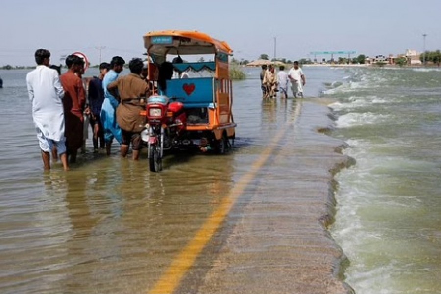 Displaced people stand on flooded highway, following rains and floods during the monsoon season in Sehwan, Pakistan, Sept 16, 2022. REUTERS