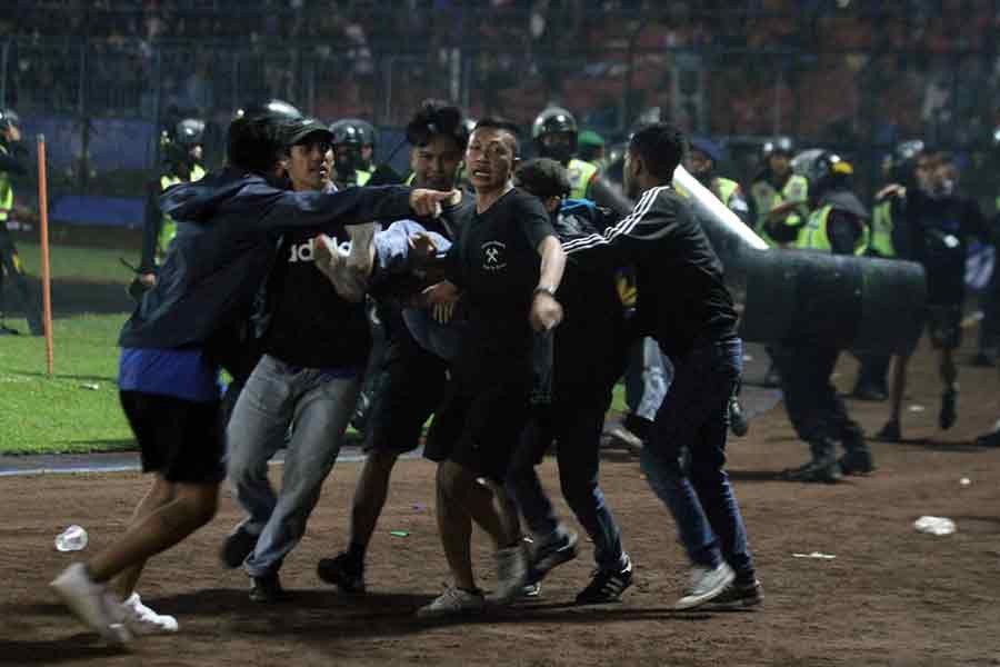 Supporters are evacuating a man hit by tear gas fired by police during the riot after the league BRI Liga 1 football match between Arema vs Persebaya at Kanjuruhan Stadium in Indonesia on Sunday –Reuters photo