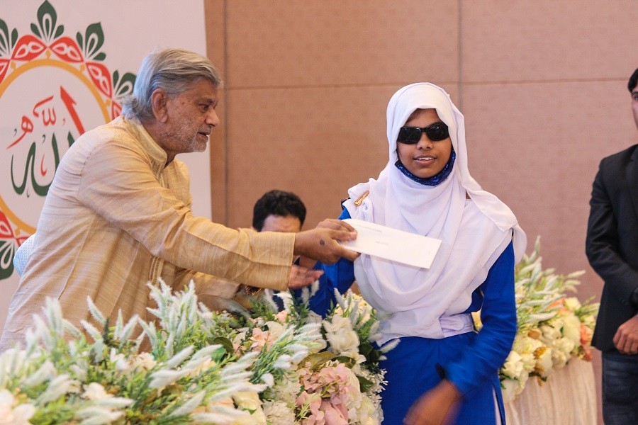 Planning Minister M A Mannan handing over award to a winner of a competition arranged to inspire visually-impaired boys and girls of different ages on the occasion of Eid e Miladunnabi at a city hotel on Sunday