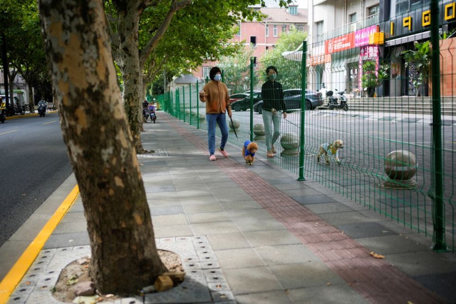 Women with dogs chat through gaps in a barrier at a sealed area, following the coronavirus disease (COVID-19) outbreak, in Shanghai, China October 11, 2022. REUTERS/Aly Song