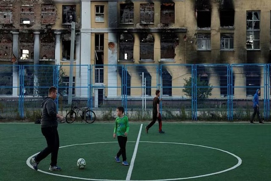 Friends play football in the playground of the School No. 134 that was destroyed by Russian military strikes, as Russia's attack on Ukraine continues, in Kharkiv, Ukraine, October 14, 2022. REUTERS/Clodagh Kilcoyne