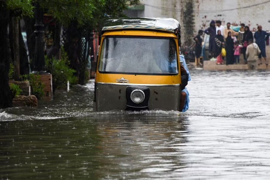 People ride a rickshaw (tuk tuk) on a flooded road, following rains during the monsoon season in Hyderabad, Pakistan Aug 24, 2022. REUTERS