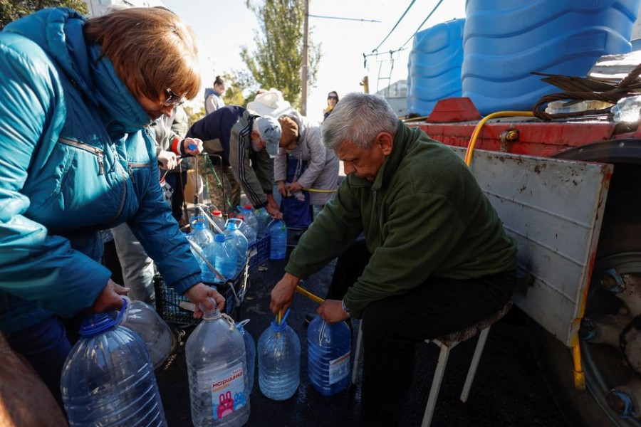 Local people fill up bottles with fresh drinking water, as the main supply pipeline for drinking water for the city was damaged in Kherson region at the beginning of Russia's attack on Ukraine, in Mykolaiv, Ukraine October 16, 2022. REUTERS/Valentyn Ogirenko