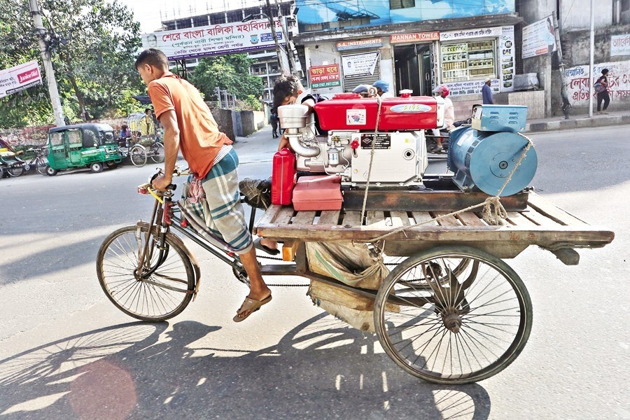 A diesel-driven generator is being carried to its destination by a rickshaw van as spotted on Hatkhola Road in Dhaka's Wari area on Saturday. Acute load-shedding for the last couple of months has contributed to the rise in sales of generators and IPSs as people are turning to these as an alternative source of power — FE photo by KAZ Sumon