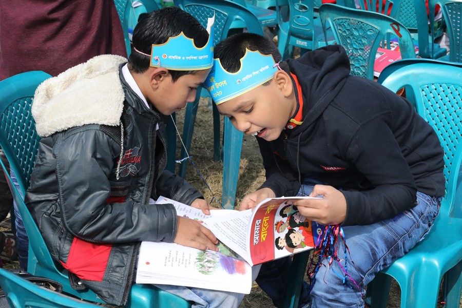 Two primary school boys browsing through their new text books in Dhaka. Strong foundation of education is essential for knowledge building. 	— FE File Photo