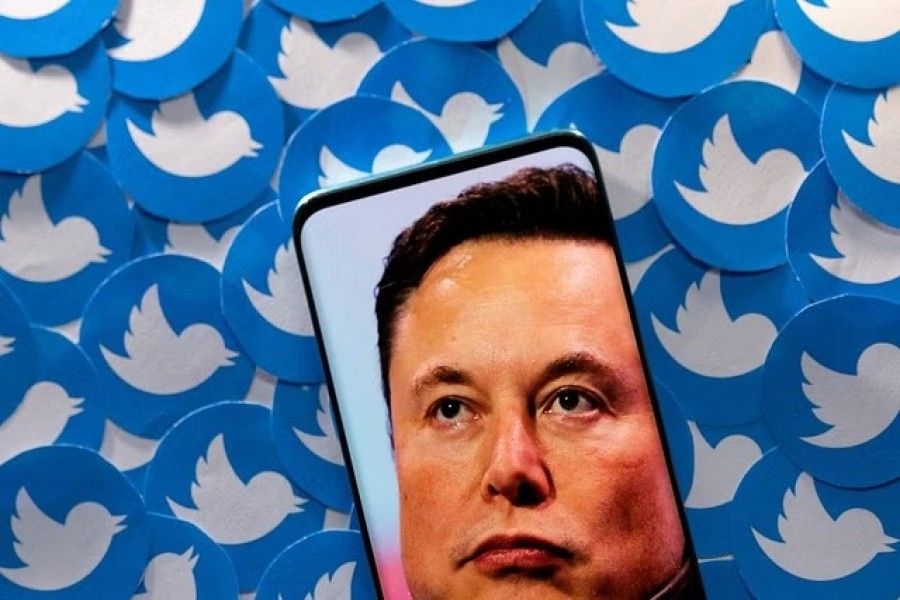 An image of Elon Musk is seen on a smartphone placed on printed Twitter logos in this picture illustration taken April 28, 2022. REUTERS