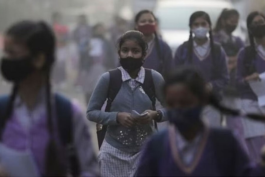 FILE PHOTO: School girls walk towards a school as they reopened after remaining closed for nearly 15 days due to a spike in air pollution, on a smoggy morning in New Delhi, India, Nov 29, 2021. REUTERS