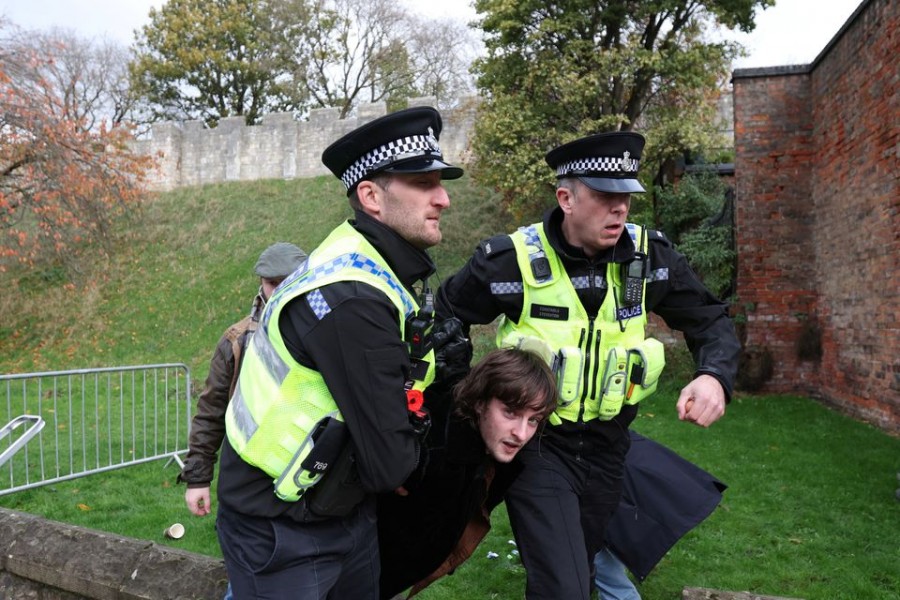 Police officers remove a man arrested for throwing an egg at King Charles during his visit to Micklegate bar in York, Britain November 9, 2022. REUTERS/Russell Cheyne