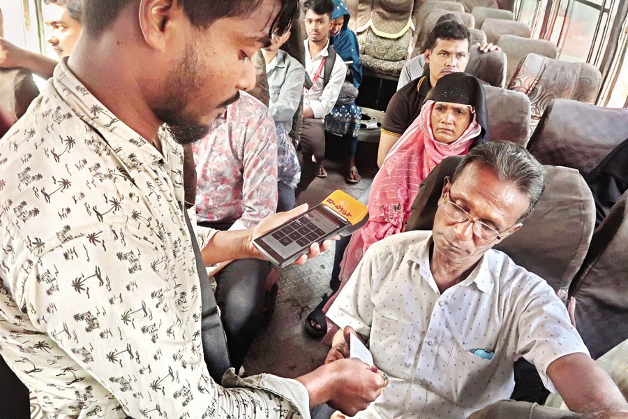 A staffer, as spotted in Dhaka's Gulistan area on Sunday, is selling tickets using a device on this Keraniganj-bound bus from Mirpur. All buses on the Mirpur route started operating under the e-ticketing system from the day. In this method, passengers will not be able to buy tickets online. Rather, they have to buy tickets through digital point of sale (POS) machines available at bus counters — FE photo by Shafiqul Alam