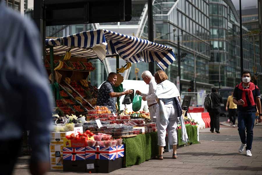 A person buying products from a fruit and vegetable market stall in central London of Britain on August 19 this year –Reuters file photo