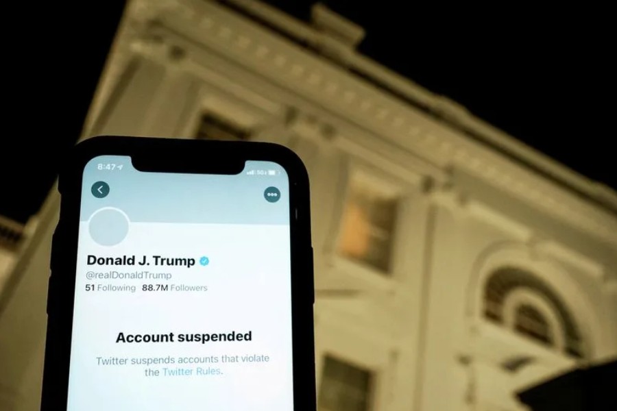A photo illustration shows the suspended Twitter account of US President Donald Trump on a smartphone and a lit window in the White House residence in Washington, US, Jan 8, 2021. REUTERS