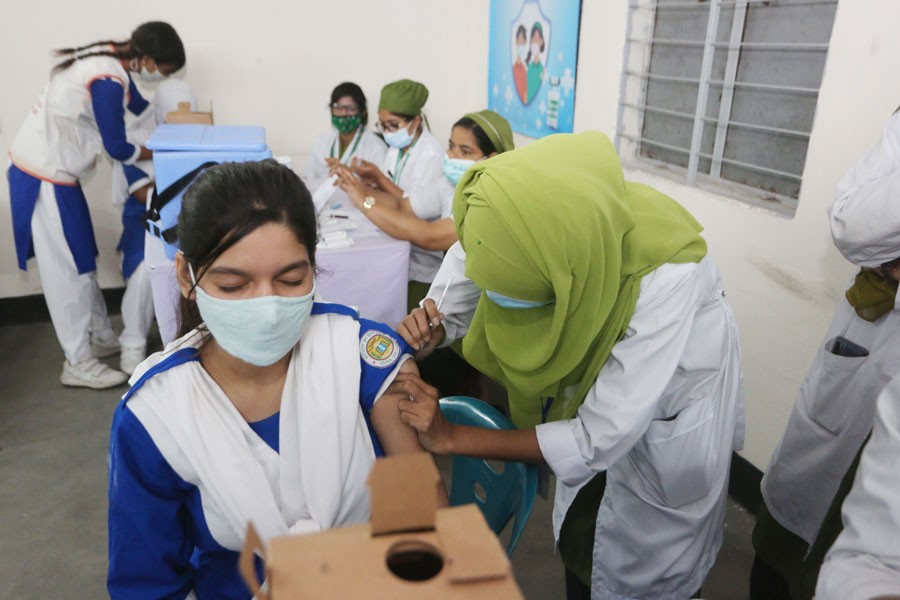 A health worker is pushing the jab to a school student in Dhaka in 2021. The decision to give vaccines free of charge was very helpful in vaccinating a large number of people in Bangladesh. 	—FE File Photo