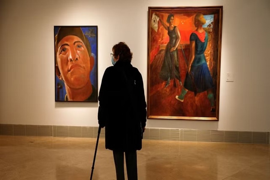 A woman looks at Kostiantyn Yeleva's "Portrait" and Semen Yoffe's "In the Shooting Gallery" during the opening of the exhibition of Ukrainian avant-garde paintings with around fifty pictures brought from the National Art Museum and the Kiev Museum of Theatre, Music and Film at the Thyssen-Bornesmiza Museum in Madrid, Spain, Nov 29, 2022. REUTERS/Juan Medina