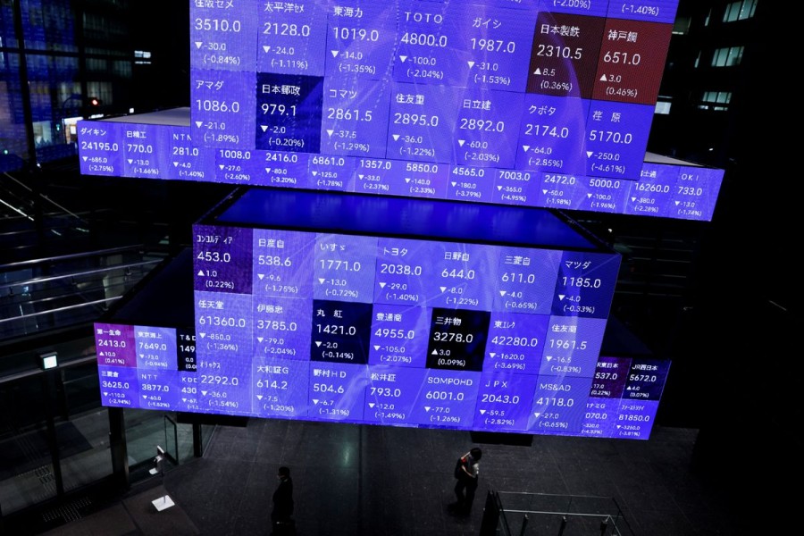 Visitors walk past Japan's Nikkei stock prices quotation board inside a conference hall in Tokyo, Japan September 14, 2022. REUTERS/Issei Kato/File Photo