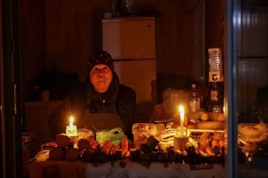 A vendor waits for customers in a small store that is lit with candles during a power outage after critical civil infrastructure was hit by Russian missile attacks, as Russia's invasion of Ukraine continues, in Odesa, Ukraine, Dec 5, 2022. REUTERS