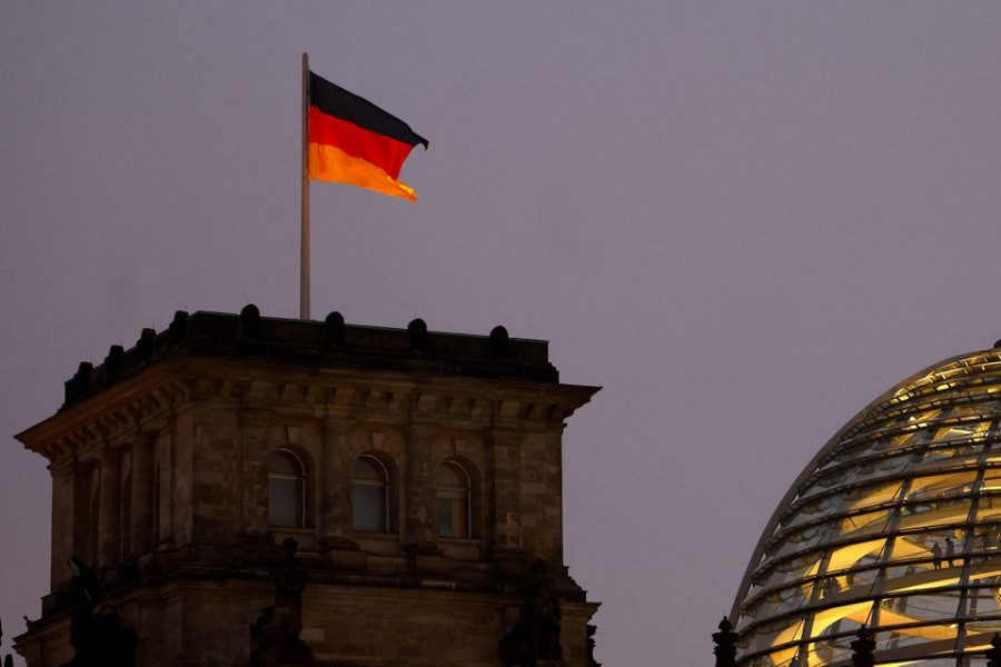 A German national flag flies atop the illuminated Reichstag building, the seat of Germany's lower house of parliament Bundestag, in Berlin, Germany December 9, 2022. REUTERS/Lisi Niesner