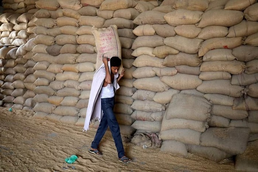 A worker carries a sack of wheat for sifting at a grain mill on the outskirts of Ahmedabad, India, May 16, 2022. REUTERS