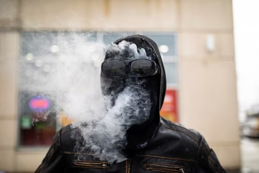 ​A counter-protestor smokes through his balaclava outside a Boston Pizza restaurant hosting an "all ages drag brunch" party in Hamilton, Ontario, Canada, Dec 11, 2022.REUTERS/FILE