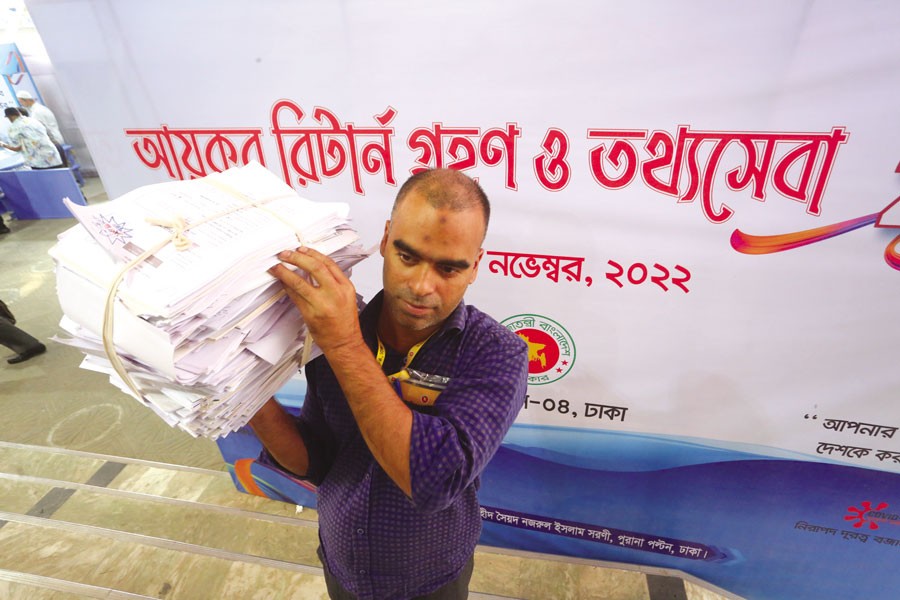 A man is carrying a set of submitted income tax returns at a tax office in Dhaka last month. —FE Photo