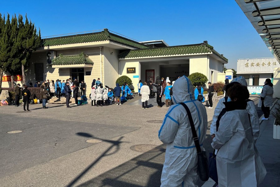People wearing personal protective equipment (PPE) stand outside a funeral home, as coronavirus disease (COVID-19) outbreak continues, in Shanghai, China December 24, 2022. REUTERS/Staff