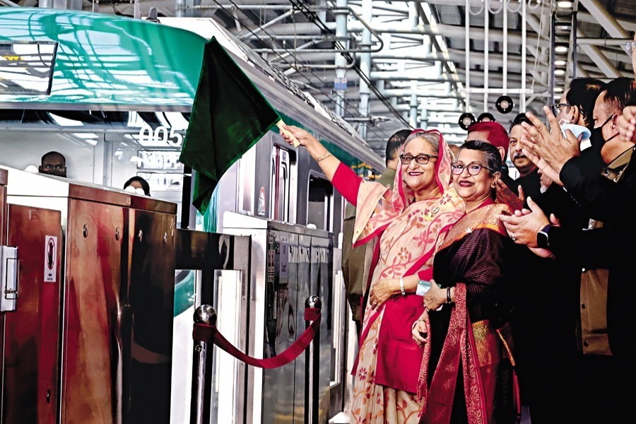 Prime Minister Sheikh Hasina waves a green flag as she inaugurates the country's first-ever metro-rail service at the Uttara North Station in Dhaka on Wednesday. The premier's younger sister, Sheikh Rehana, was also present on the occasion — BSS