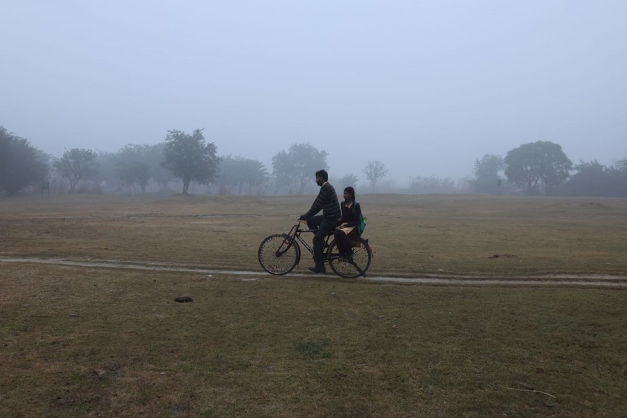 A man cycles with a schoolgirl on the pillion as they are on their way to school on a cold winter morning in New Delhi, India, January 5, 2023. REUTERS/Anushree Fadnavis