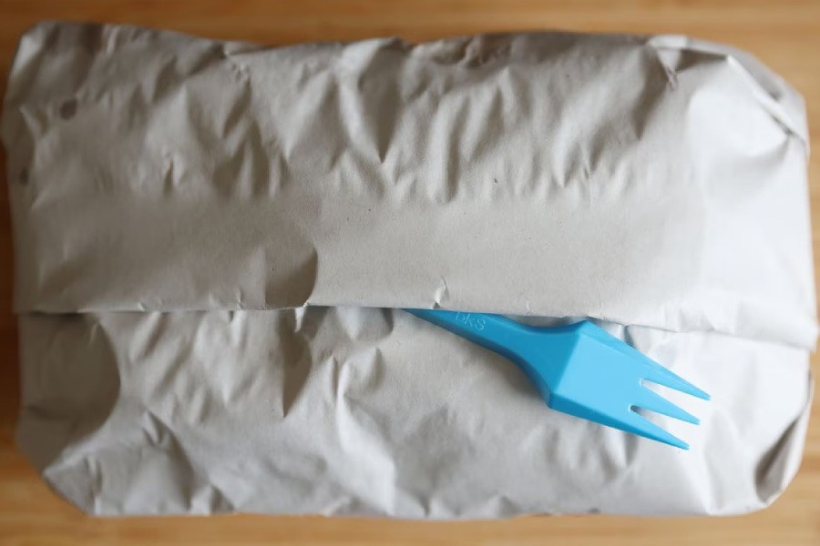 A plastic fork sticks out from a wrapped portion of fish and chips from a fish and chip shop in Manchester, Britain, May 18, 2022. Picture taken May 18, 2022. REUTERS/Phil Noble/File Photo