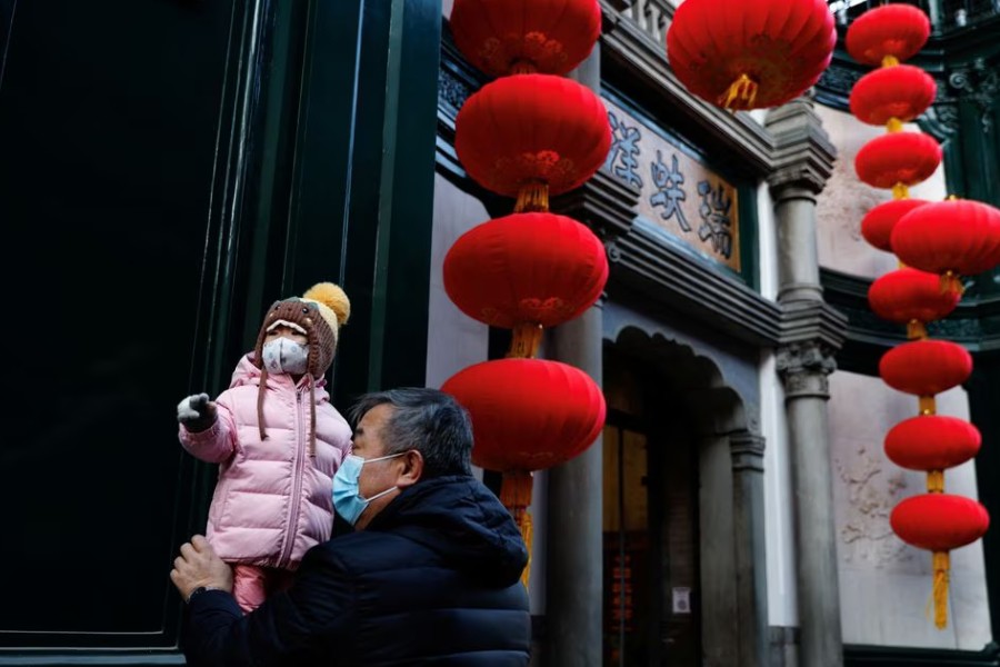 An elderly person holds a child near lanterns decorating a shop ahead of the Chinese Lunar New Year, in Beijing, China, January 15, 2023. REUTERS/Tingshu Wang