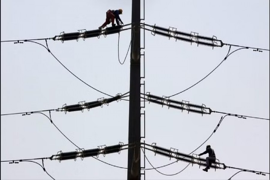 Employees of K-Electric fix cables on a power transmission tower in Karachi, Pakistan, Aug 22, 2016. REUTERS