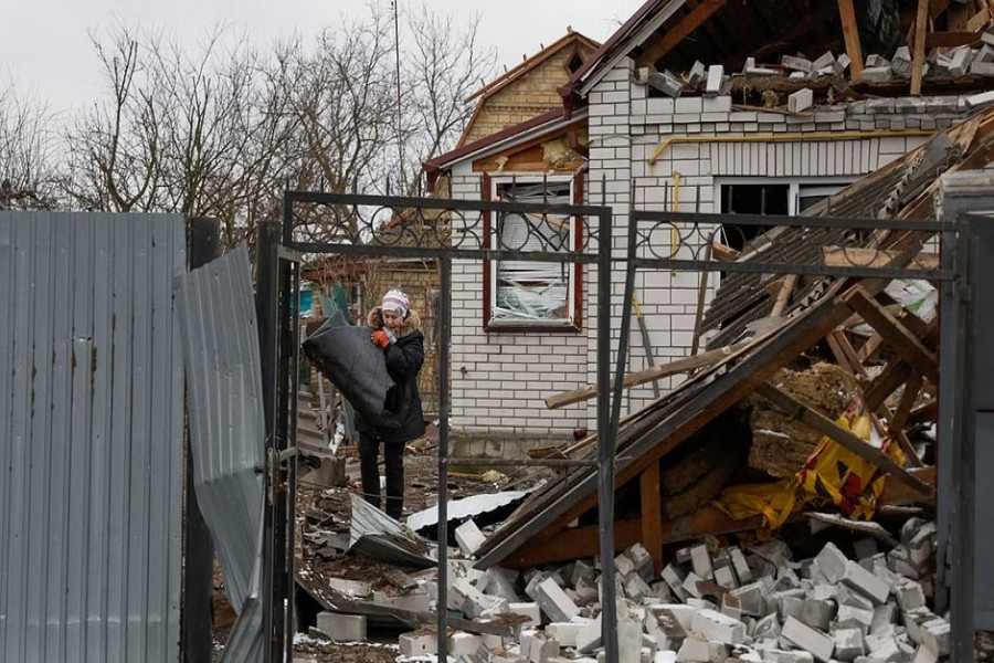 A local resident removes debris from a house of her neighbour damaged by a Russian military strike, amid Russia's attack on Ukraine, in the town of Hlevakha, outside Kyiv, Ukraine Jan 26, 2023. REUTERS