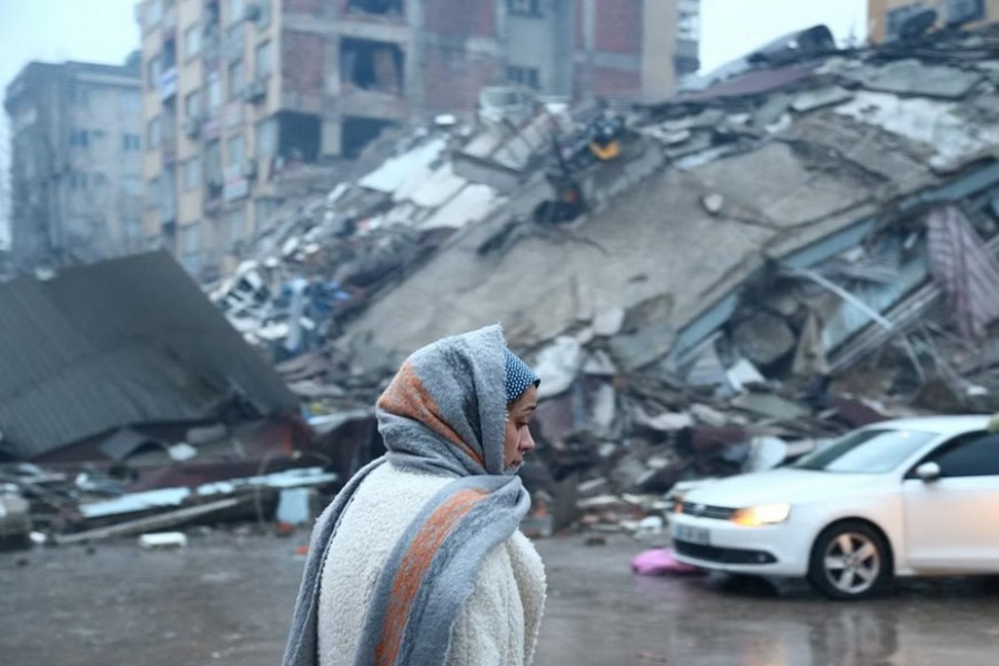 A woman stands near a collapsed building after an earthquake in Kahramanmaras, Turkey February 6, 2023. |REUTERS