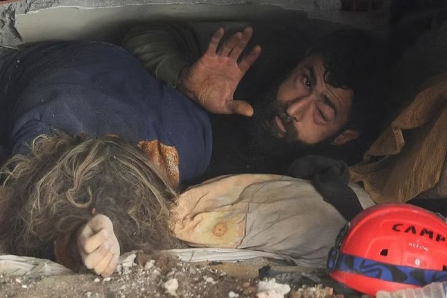 Abdulalim Muaini lies under the rubble next to the body of his wife Esra, in the aftermath of a deadly earthquake in Hatay, Turkey, Feb 8, 2023. REUTERS