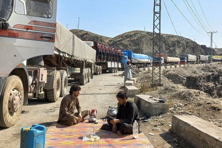 Men sit near a queue of trucks loaded with supplies to leave for Afghanistan, after Taliban authorities have closed the main border crossing in Torkham, Pakistan on February 21, 2023 — Reuters photo