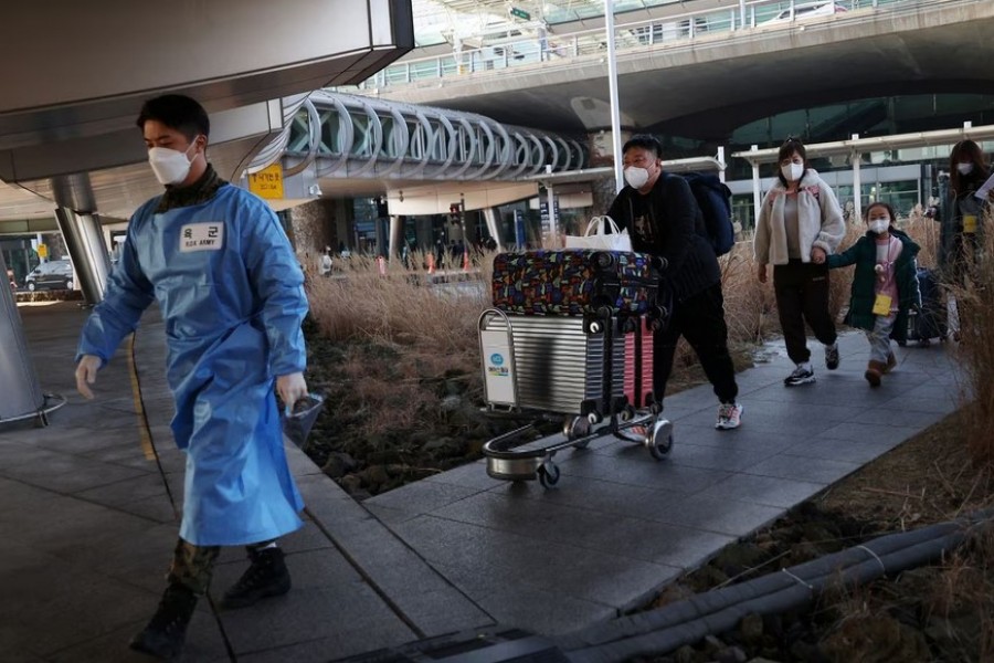 A South Korean soldier wearing personal protective equipment (PPE) leads a group of Chinese tourists to the coronavirus disease (COVID-19) testing centre upon their arrival at the Incheon International Airport in Incheon, South Korea, January 12, 2023. REUTERS/Kim Hong-Ji